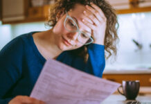 Woman in glasses revieiwing insurance info sheet