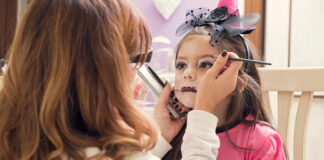 Mother applying make-up on daughter for Halloween
