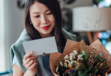 Woman holding flowers and reading a card
