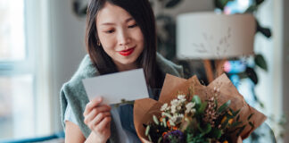 Woman holding flowers and reading a card