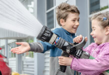 2 children spraying water with a hose