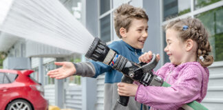 2 children spraying water with a hose