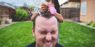 Girl popping water balloon on father’s head