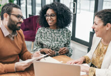 3 people gathered around computer and talking
