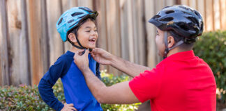 Man fastening helmet on child’s head