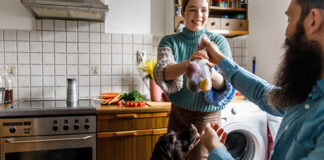 Man passing woman a bag of produce in the kitchen