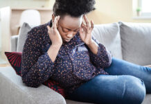 Woman sitting down holding her head in pain