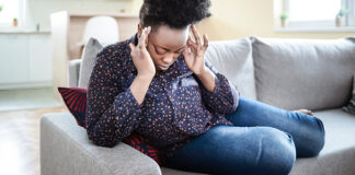 Woman sitting down holding her head in pain