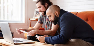 2 men reviewing paperwork at a computer