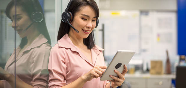 A woman wearing headphones and looking at a tablet